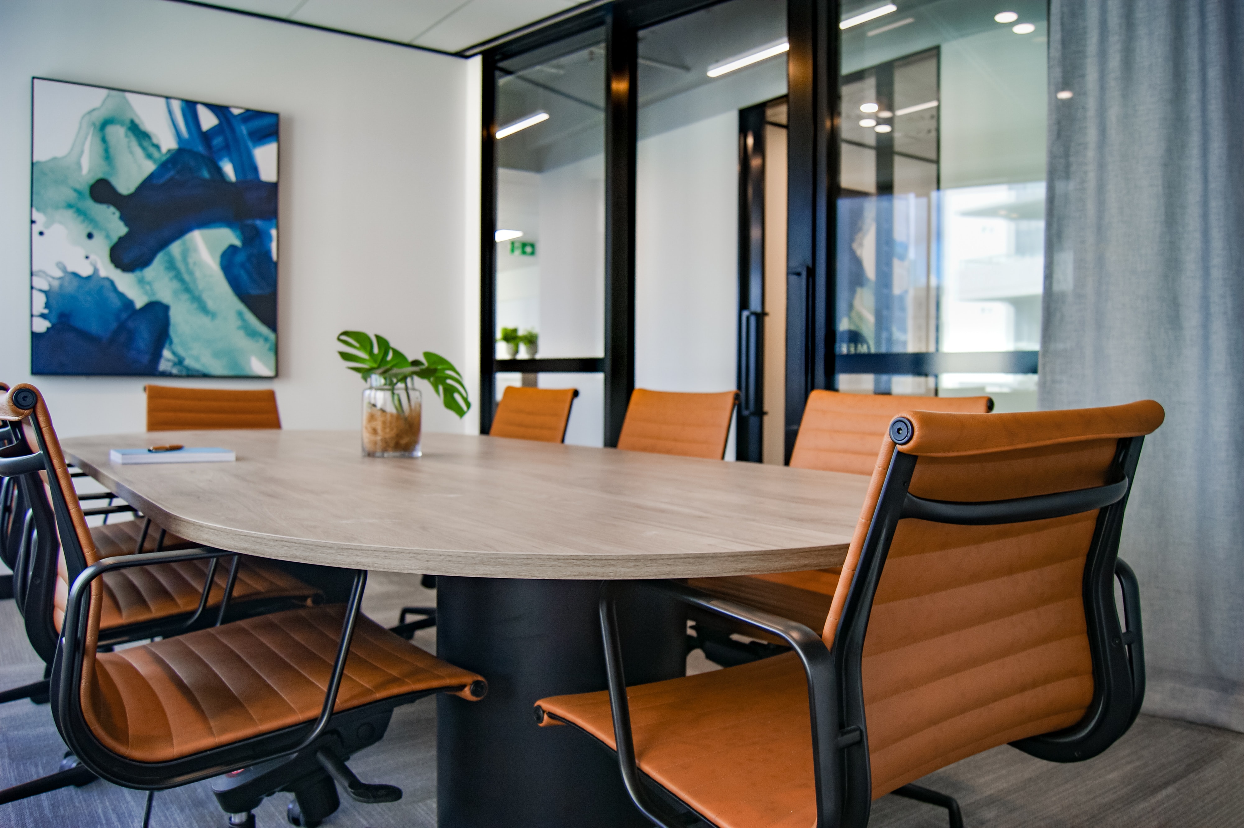 photo of modern lokking conference room with a rounded table surrounded by orange office chairs